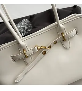 Detailed close-up of cream leather tote bag with elegant gold metal hook and fine stitching