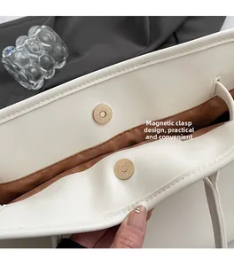 Detail view of the magnetic snap closure on a minimalist white faux leather tote bag