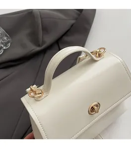Detail of cream white leather handbag featuring a round golden rotating clasp and sturdy handle