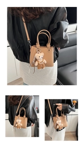 Detail view of camel pebble leather handbag with cute plush bear charm and crossbody strap