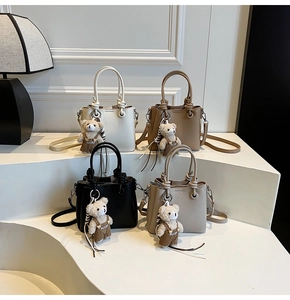 Litchi texture bucket bags in four colors with cute teddy bear charms on white steps