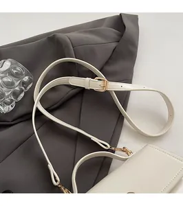 Close-up of adjustable beige leather shoulder strap with gold metal buckle on a square handbag