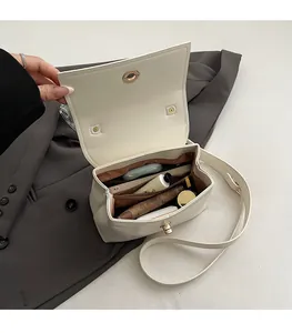 Detail showing the spacious multi-compartment interior of white leather crossbody bag