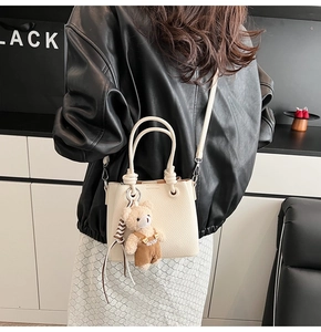 Minimalistische cremeweiße Beuteltasche mit einem niedlichen Teddybär-Anhänger-Detail