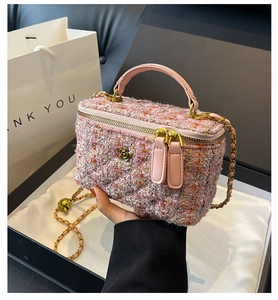 Close-up of pink tweed mini bag featuring gold camellia buckle and chain strap detail