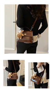 Detail of brown faux leather crossbody bag with gold twist lock and cute bear charm