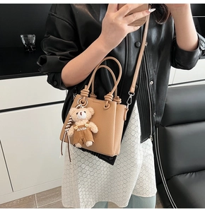 Mirror selfie showing mini litchi pattern bucket bag with cute teddy bear pendant