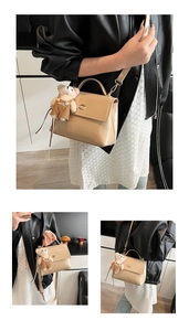 Detail of crossbody bag with metal twist lock, adjustable strap, and cute bear charm