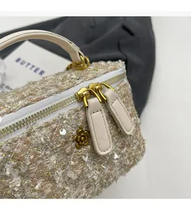 Detailed macro view of the smooth gold zipper and tweed fabric on the box handbag