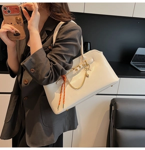 Dettaglio borsa bianca in pelle con catena dorata e corda intrecciata arancione