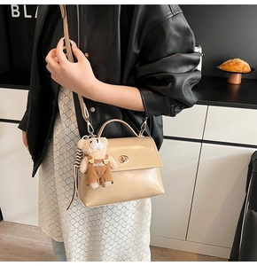 Detail of apricot crossbody bag with a cute bear charm and golden rotating lock buckle