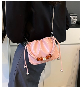 Detail of pink pleated bucket bag with braided handle, beads, and silver chain strap