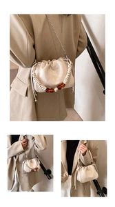 Detail of beige bucket bag featuring pleated PU leather and decorative beaded woven handle