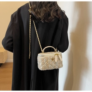 Detail of tweed crossbody bag with gold chain and flower buckle on black coat