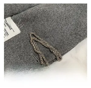 Macro shot of silver woven chain and gray wool fabric texture with white design label
