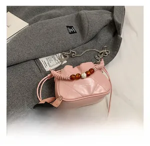 Close-up of pink quilted bucket bag with pearl beaded handle and metal chain strap