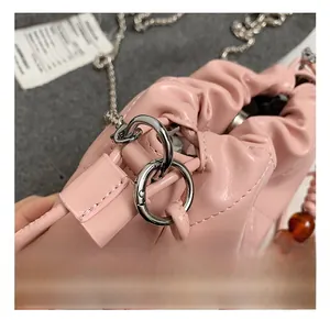 Detail of pink quilted handbag with amber beaded handle and silver chain link