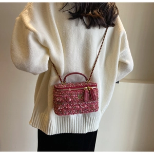 Detail of pink and red tweed mini box bag with gold floral clasp on white sweater