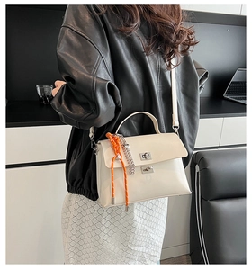 Detail of cream white faux leather crossbody bag with silver twist lock and woven rope
