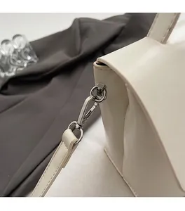 Detail of premium silver metal buckle and textured off-white leather shoulder bag
