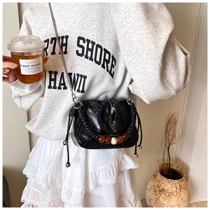 Detail of black crossbody bucket bag featuring acrylic beads and woven handle