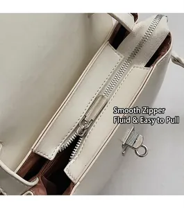 Detail view of the smooth silver zipper and brown fabric lining of the white messenger bag
