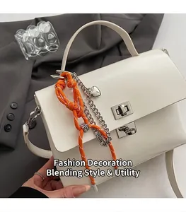 Close-up of white leather messenger bag featuring silver twist lock and charm detail