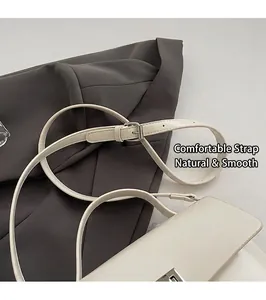 Detail of adjustable leather shoulder strap with silver buckle on cream crossbody bag