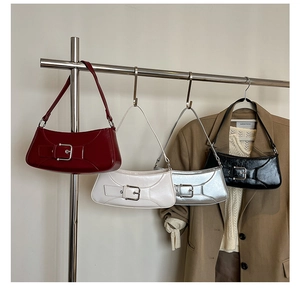 Close-up of four minimalist baguette bags with metallic buckle on glossy leather finish