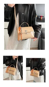 Detail view of apricot patent leather handbag with orange braided rope charm and silver lock