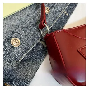 Detailed macro view of dark red leather shoulder bag with silver rings and precise stitching