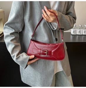 Detail showing the shiny red leather texture and silver buckle of the baguette bag