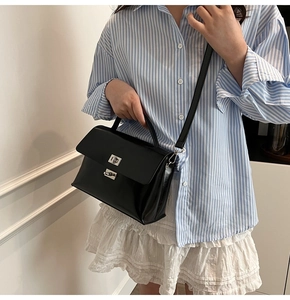Classic black leather satchel bag with silver clasp styled with a striped shirt and skirt