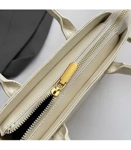 Détail de la fermeture éclair dorée sur un sac à main beige en similicuir