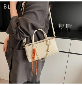 Sac à bandoulière beige avec chaîne dorée, breloque cœur et détail tissé orange