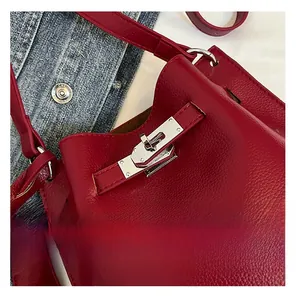 Macro shot of red pebble leather bucket bag featuring a silver metal buckle closure