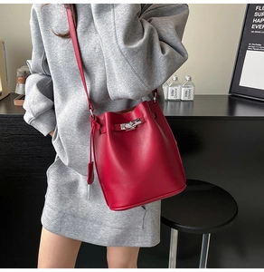 Detailed close-up of dark red pebble leather bucket bag with silver metal buckle closure
