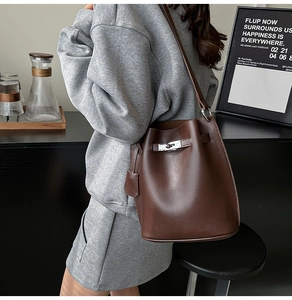 Detail view of dark brown pebbled leather bucket bag with silver metal swivel lock