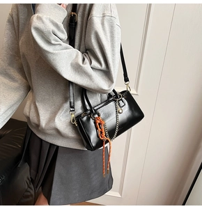 Vue latérale d'un sac à main en cuir huilé noir avec corde orange et chaîne dorée