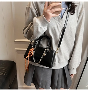 Détail du sac à main en cuir ciré noir avec chaîne cœur dorée et pendentif orange