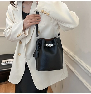 Detail of silver twist lock and pebble leather texture on a black bucket bag