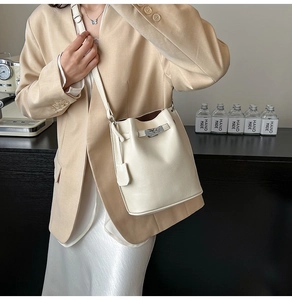 Detail of the chic beige bucket bag featuring a metal clasp and pebbled leather texture