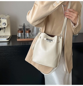 Detail of off-white bucket bag with lychee grain leather and silver metal lock closure