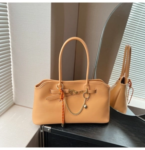 Close-up of beige tote with golden chain heart pendant and woven rope detail