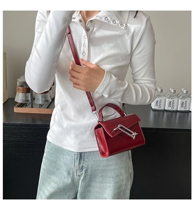 Détail du mini sac en cuir rouge brillant avec boucle épingle argentée et bandoulière