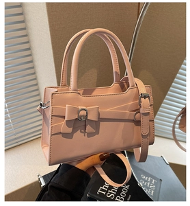 Detailed view of pink faux leather handbag with decorative bow and silver metal buckle