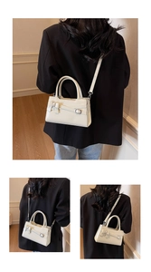 Detail of white mini crossbody bag with bow accent and silver buckle on black blazer
