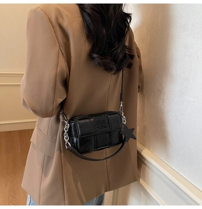 Détail du sac bandoulière tressé noir avec pendentif étoile et bandoulière chaîne
