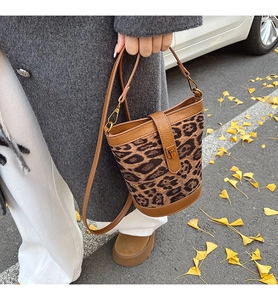 Detail of leopard print suede bucket bag with gold lock buckle and leather strap