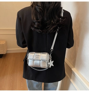 Détail du sac à bandoulière tressé argenté avec étoile et chaîne porté par un mannequin